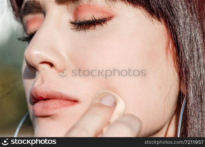 beautiful young Caucasian girl brown haired apply Foundation on face outside