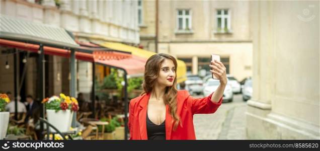 Beautiful young caucasian tourist woman takes a selfie in a European city. Tourist woman takes a selfie