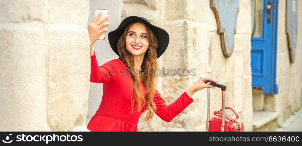 Beautiful young caucasian woman in black hat looking on the smartphone smiling and sitting on stairs at the door outdoors. Beautiful young caucasian woman in black hat looking on the smartphone smiling and sitting on stairs at the door outdoors.