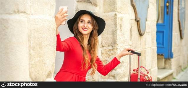 Beautiful young caucasian woman in black hat looking on the smartphone smiling and sitting on stairs at the door outdoors. Beautiful young caucasian woman in black hat looking on the smartphone smiling and sitting on stairs at the door outdoors.