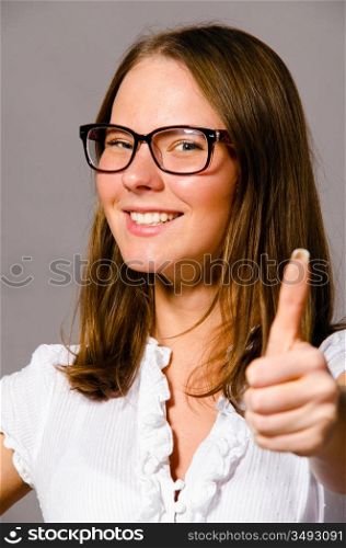beautiful young caucasian woman on gray background is showing thumbs up