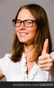 beautiful young caucasian woman on gray background is showing thumbs up
