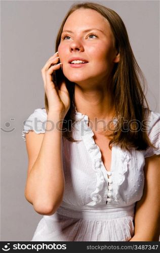 beautiful young caucasian woman on gray background is talking phone