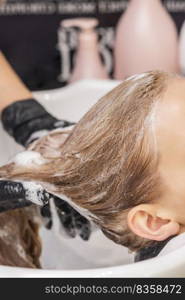 Beautiful young caucasian woman receiving wash her hair in a hair salon. Woman receiving wash her hair