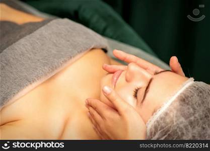 Beautiful young caucasian woman with closed eyes receiving a facial massage in a beauty salon. Beautiful young caucasian woman with closed eyes receiving a facial massage in a beauty salon.