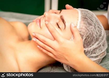 Beautiful young caucasian woman with closed eyes receiving a facial massage in a beauty salon. Beautiful young caucasian woman with closed eyes receiving a facial massage in a beauty salon.