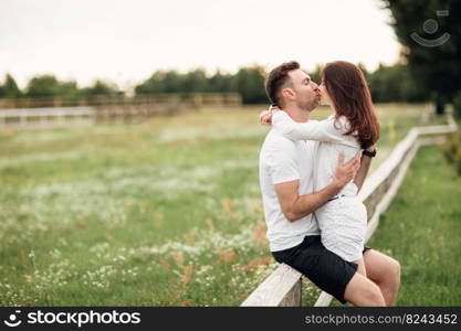 beautiful young couple hugging and kissing outdoors in the park on a warm summer sunny day.. beautiful young couple hugging and kissing outdoors in the park on a warm summer sunny day