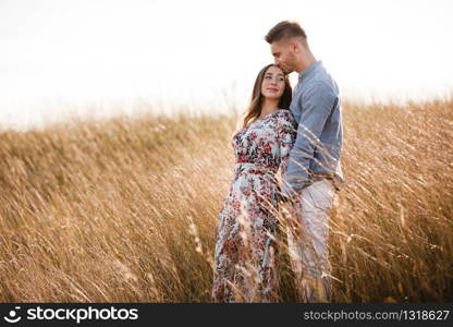 beautiful young couple hugging in a field with grass at sunset. stylish man and woman having fun outdoors. family concept. copy space. beautiful young couple hugging in a field with grass at sunset. stylish man and woman having fun outdoors. family concept. copy space.