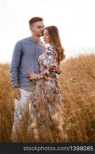 beautiful young couple hugging in a field with grass at sunset. stylish man and woman having fun outdoors. family concept. copy space. beautiful young couple hugging in a field with grass at sunset. stylish man and woman having fun outdoors. family concept. copy space.