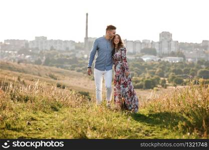 beautiful young couple in love hugging and smiling outdoors on city background. stylish romantic woman with long hair have a good time with man. copy space.. beautiful young couple in love hugging and smiling outdoors on city background. stylish woman have a good time with man. copy space