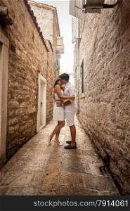 Beautiful young couple in love kissing on old narrow street