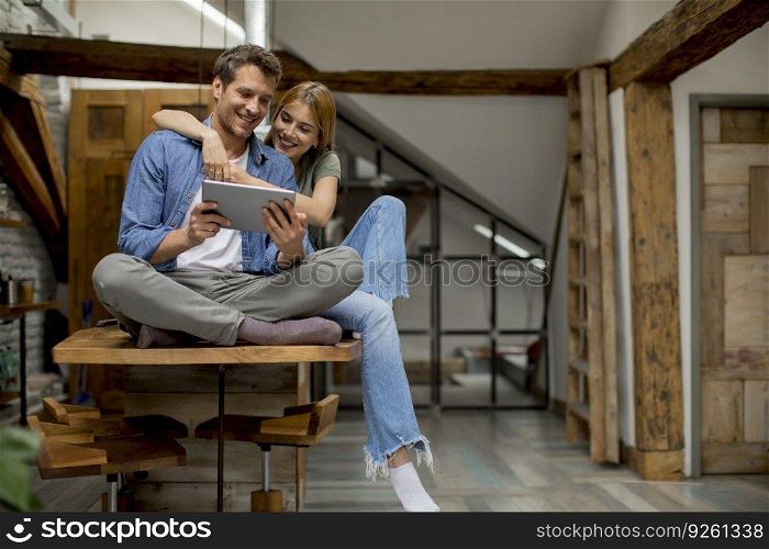 Beautiful young couple is using a digital tablet and smiling in kitchen at home
