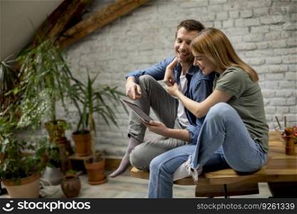 Beautiful young couple is using a digital tablet and smiling in kitchen at home