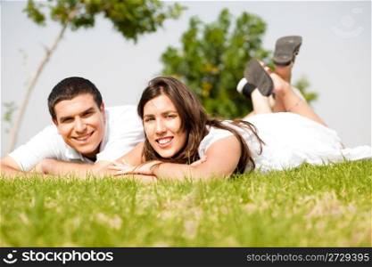beautiful young Couple lie down on grass and smile