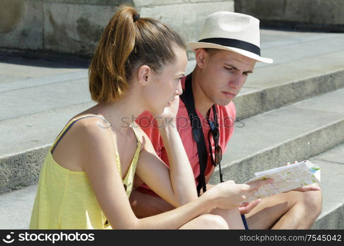 beautiful young couple sitting and holding a map