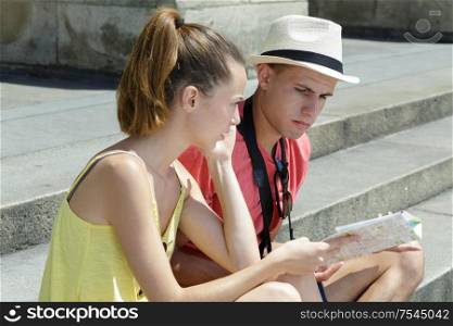 beautiful young couple sitting and holding a map