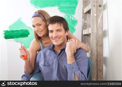 Beautiful young couple sitting together with color roller at home