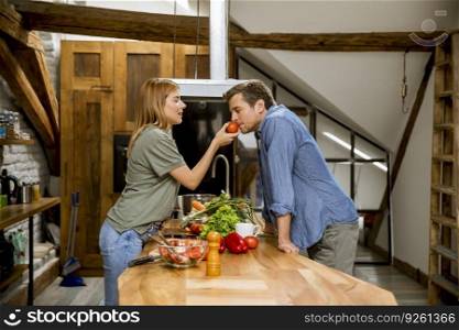 Beautiful young couple smiling while cooking in kitchen at loft apartment