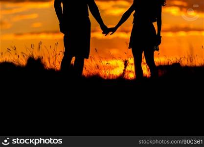 Beautiful young couple standing the sunset. Scenic landscape view with sunset. two hold hands. Beautiful young couple standing the sunset. two hold hands. Scenic landscape view with sunset.