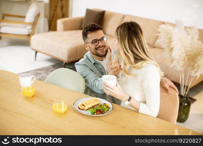 Beautiful young couple talking and smiling while eating healthy  at home.