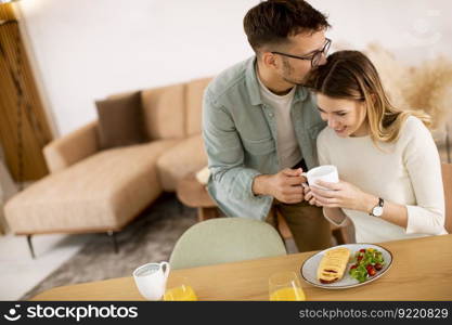 Beautiful young couple talking and smiling while eating healthy  at home.