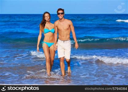 Beautiful young couple walking in the beach shore on summer vacation