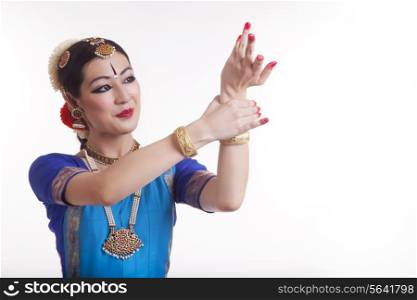 Beautiful young dancer performing Bharatanatyam over white background