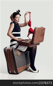 Beautiful young fashion woman opening a suitcase and holding a red under braw