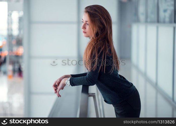 Beautiful young female posing on glazed balcony. Airport at the background.