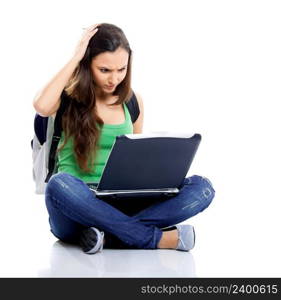 Beautiful young female student sitting on floor studying on a laptop, isolated on white