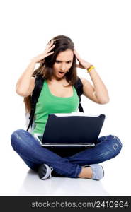 Beautiful young female student sitting on floor studying on a laptop, isolated on white