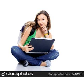 Beautiful young female student sitting on floor studying on a laptop, isolated on white
