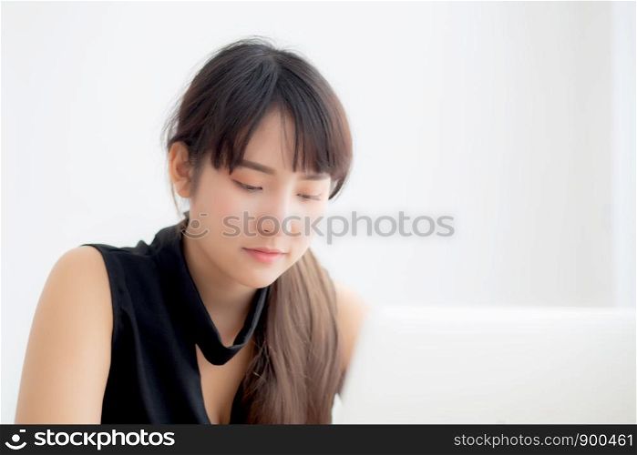 Beautiful young freelance asian woman smiling working and typing on laptop computer at desk office with professional, girl using notebook checking email or social network, business and lifestyle concept.