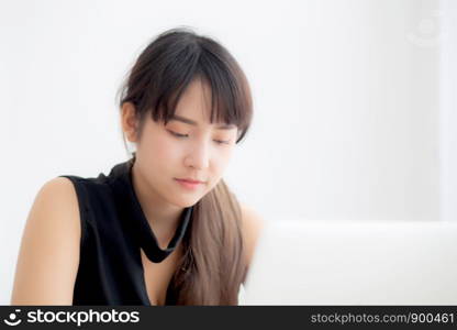 Beautiful young freelance asian woman smiling working and typing on laptop computer at desk office with professional, girl using notebook checking email or social network, business and lifestyle concept.