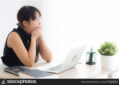 beautiful young freelance asian woman working bored and tired on laptop computer at the office, girl lazy sleepy and yawning on notebook, female secretary with exhausted, business concept.