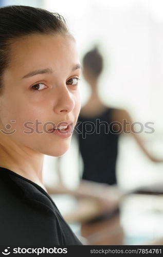 Beautiful young girl close up with ballerina in the blurry background