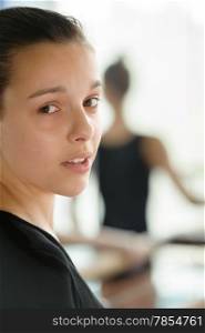 Beautiful young girl close up with ballerina in the blurry background