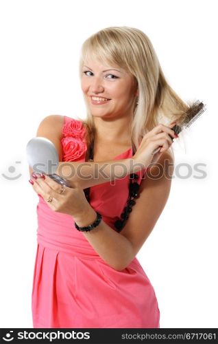 Beautiful young girl combing her hair before a mirror with a white background