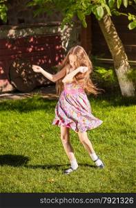 Beautiful young girl dancing on grass at sunny day