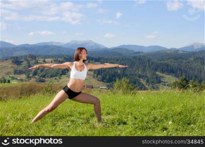 Beautiful young girl doing yoga exercise at the summer meadow