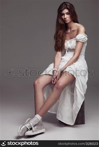 Beautiful young girl fashion girl in white dress on grey background