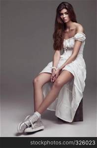 Beautiful young girl fashion girl in white dress on grey background