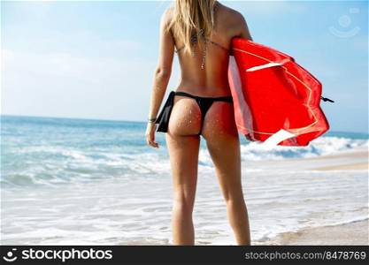 Beautiful young girl holding a surfboard and checking the waves
