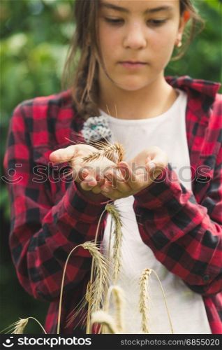 Beautiful young girl holding golden wheat ear