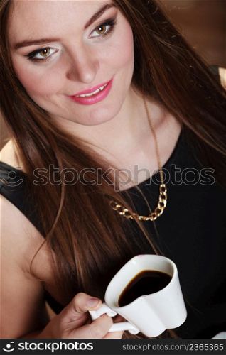 Beautiful young girl holding heart shaped cup of coffee drinking, unusual high angle view