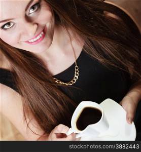 Beautiful young girl holding heart shaped cup of coffee drinking, unusual high angle view
