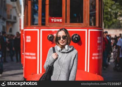 Beautiful young girl in fashionable clothes poses in front of tram at popular Istiklal street in Istanbul,Turkey