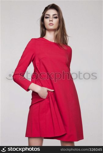 Beautiful young girl in red dress fashion on grey background
