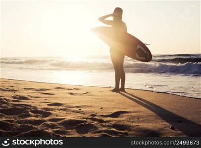 Beautiful young girl in the beach with her surfboard
