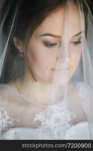 Beautiful young girl is in a wedding decoration next to window